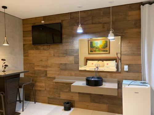 baño con pared de madera con lavabo y TV en Pousada Hibisco, en Serra do Cipo