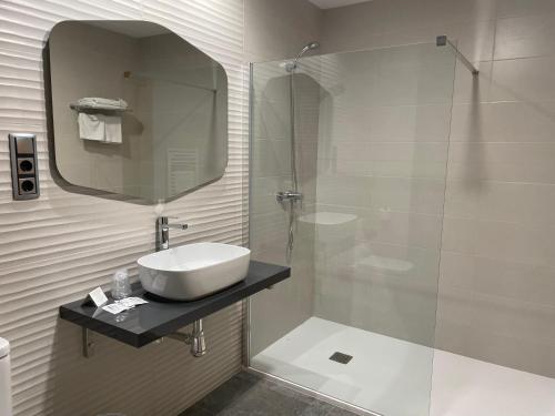 a bathroom with a sink and a shower with a mirror at Hostal Pirineos Ainsa in Aínsa