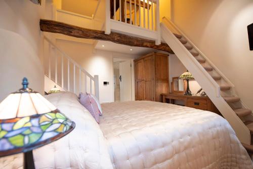 a bedroom with a white bed and a staircase at Neroli River View Apartment in Bourton on the Water