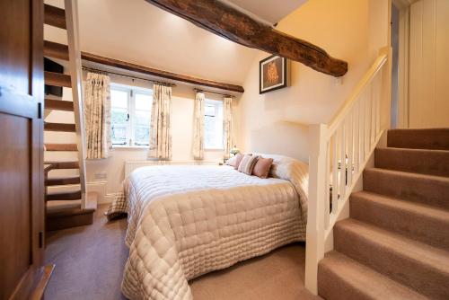 a bedroom with a bed and a staircase at Neroli River View Apartment in Bourton on the Water