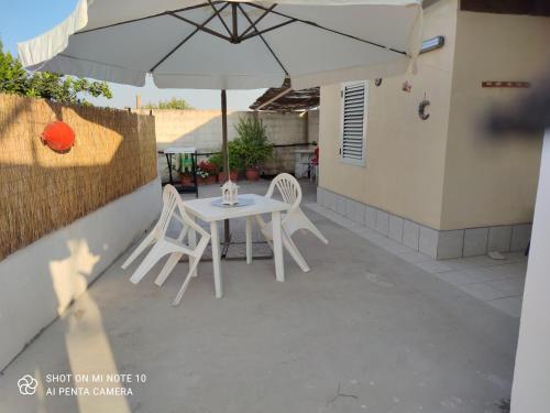 サンタ・マリア・デル・フォカッロにあるCasa Vacanza Della Malva 14のパティオ(パラソルの下に白いテーブルと椅子付)