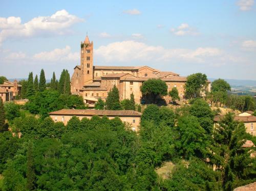 un grande edificio in cima a una collina con alberi di Vacanze Senesi a Siena