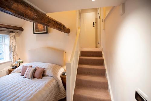 a bedroom with a white bed and a staircase at Neroli River View Apartment in Bourton on the Water