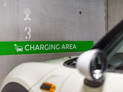 a white car parked next to a green charging area sign at Hotel Adapura Wagrain in Wagrain