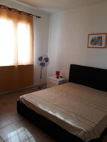 a bedroom with a bed and a fan and a window at La Tanca in Siniscola