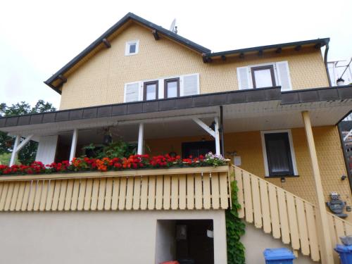 Casa amarilla con balcón con flores rojas en Ilkas Inn, en Vielbrunn