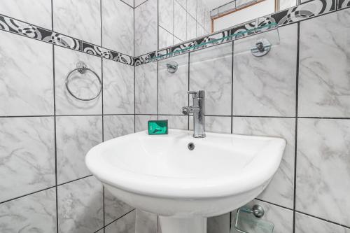 lavabo blanco en el baño con azulejos de mármol en Ayenda Casa Aika en Lima