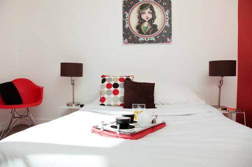 a bedroom with a white bed with a red chair at Les Canisses in Saint-Pierre-la-Garenne