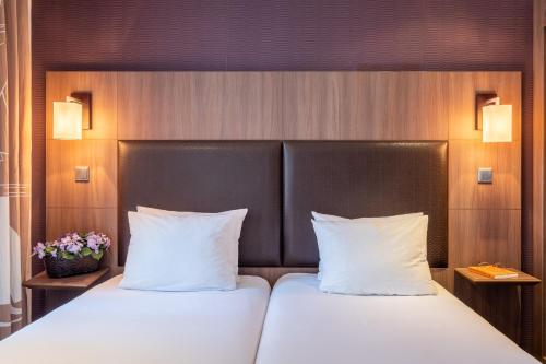 a bedroom with a bed with white pillows and flowers at Hotel London in Paris