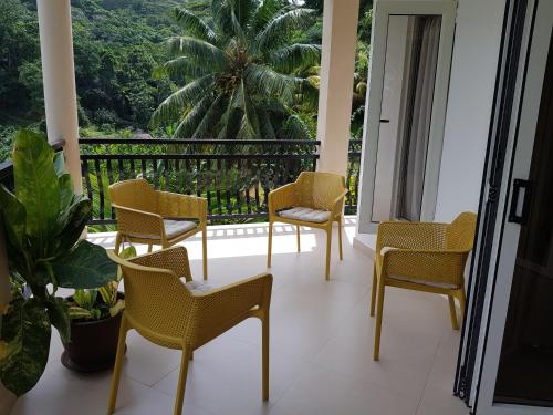 a balcony with chairs and a view of a palm tree at SOUTH HILL VILLA in Mahe