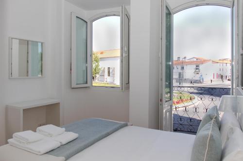 a white bedroom with a bed and two windows at Varandas do Nabão in Tomar