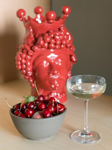 a bowl of cherries next to a glass of wine at Criu Boutique Hotel in Nicolosi
