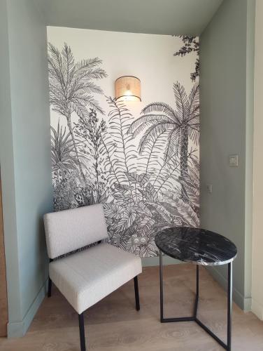 a chair and a table in a room with a mural at Les Galets Hôtel et B&B in Bandol
