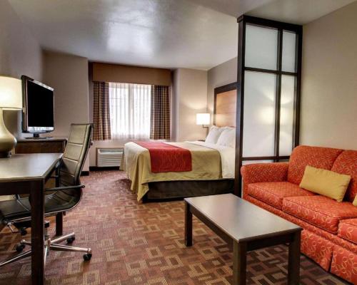 a hotel room with a bed and a couch and a desk at Days Inn by Wyndham Jackson Downtown in Jackson