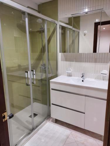 a bathroom with a glass shower and a sink at Casa del Beso II in Luarca