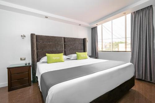 una camera da letto con un grande letto bianco con due cuscini verdi di Ayenda Casa Aika a Lima
