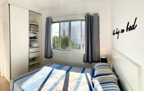um quarto com uma cama e uma janela em 505 - Apartamento Lindo, amplo e decorado, mobiliario moderno, cozinha completa com utensílios , Excelente vista da cidade e localização privelegiada no bairro Bigorrilho proxímo de shopping e parques em Curitiba