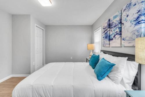 a white bedroom with a large bed with blue pillows at Dave and Busters, Outlets, Convention Center across street w Parking - Sleeps 15 in Atlantic City