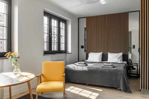グダニスクにあるBY THE RIVER apartmentsのベッドルーム1室(ベッド1台、黄色い椅子付)