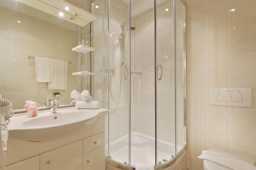 a white bathroom with a shower and a sink at Apparthotel Tom Sojer in Ellmau