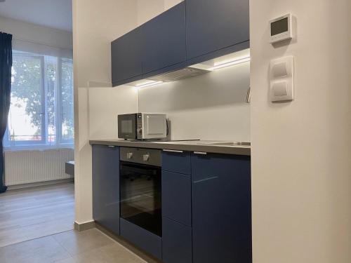 cocina con armarios azules y microondas en Jogász Street - A. Apartman, en Pécs
