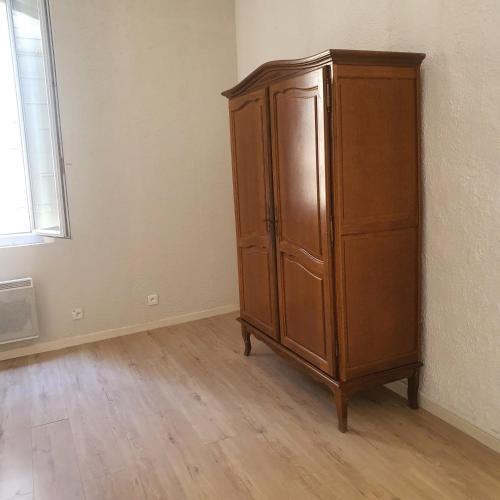 une armoire en bois dans une pièce à côté d'une fenêtre dans l'établissement Liberté17/2, à Arles