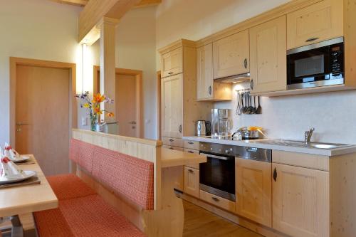 a kitchen with wooden cabinets and a sink and a stove at Apparthotel Tom Sojer in Ellmau