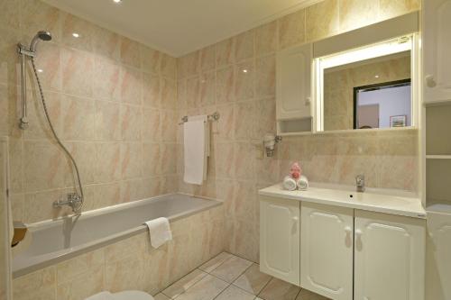 a bathroom with a bath tub and a sink at Apparthotel Tom Sojer in Ellmau
