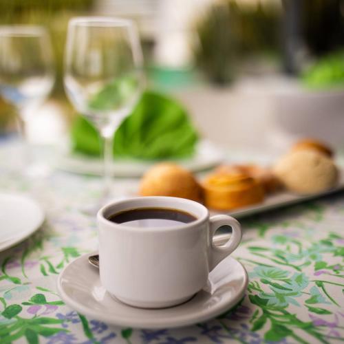 a cup of coffee on a table with a plate of food at Hotel Horizon & Convention Center in Morelia