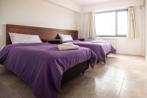 two beds in a room with purple blankets at Edificio Pampa II in Añelo