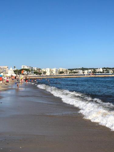 a beach with people walking on the sand and the water at Studio Bijou Plage Antibes Juan-les-Pins in Antibes