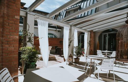 un patio con sillas y mesas blancas y un edificio en Hotel Cavallo Bianco, en Reggiolo