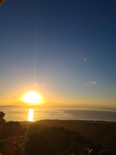 a sunset over the ocean with the sun in the sky at Peaceful House in Vieux-Habitants