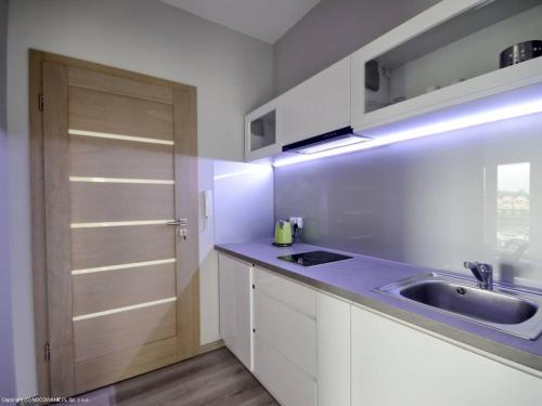 a kitchen with white cabinets and a sink and a door at Platinium in Karwia