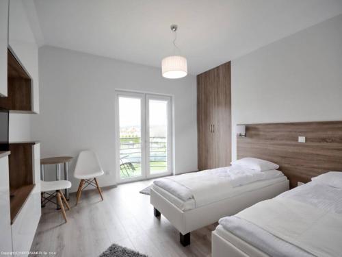 a white bedroom with two beds and a window at Platinium in Karwia