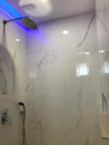 La salle de bains est pourvue d'une douche et d'un mur en marbre blanc. dans l'établissement Village Inn Studios & Family Apartments, à Laganas