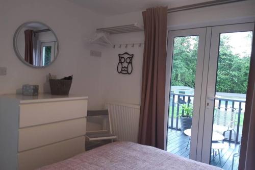 a bedroom with a bed and a mirror and a balcony at Chalet 174 Glan Gwna Park Caernarfon in Caeathro