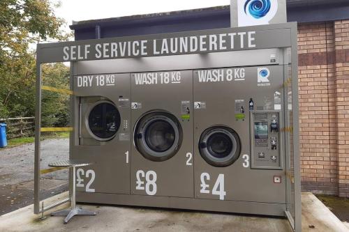 a self service laundry machine in front of a building at Chalet 174 Glan Gwna Park Caernarfon in Caeathro