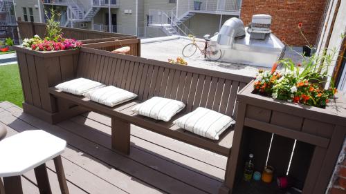 a wooden bench with pillows and flowers on a patio at HoMa Homestay Hotel by Olympic Stadium Montreal Auberge-Hostel in Montréal