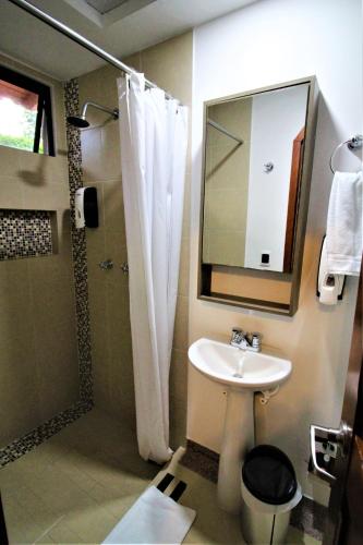 a bathroom with a sink and a shower with a mirror at Amazilia Hotel in Pereira