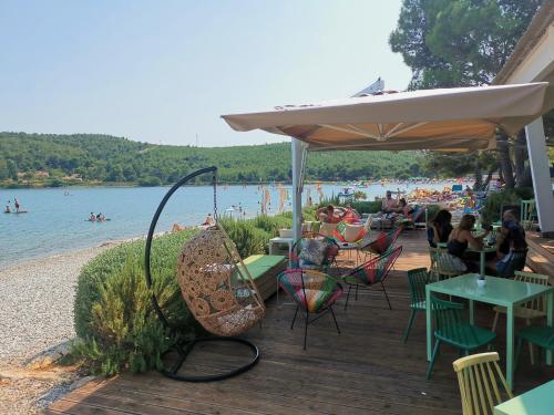 a patio with tables and chairs and people on the beach at Large camper in the olive grove in Banjole