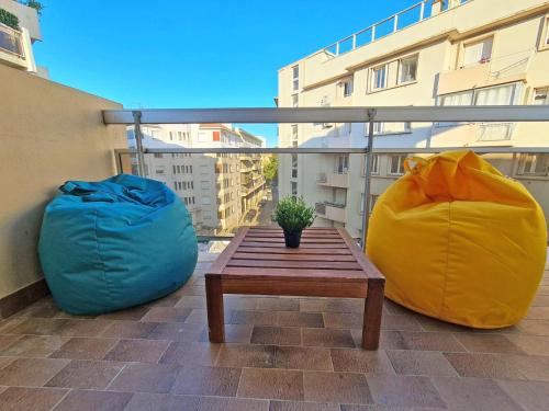 2 poufs et une table en bois sur un balcon dans l'établissement GregBnb - T2 Pleine Ville - CLIMATISE - BALCON - 2, à Toulon