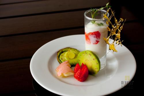 a white plate with fruit and a glass of milk at Mercury Central Hotel Hanoi in Hanoi