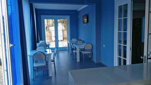 Habitación con paredes azules, mesas y sillas. en Guest House Marineza en Gonio