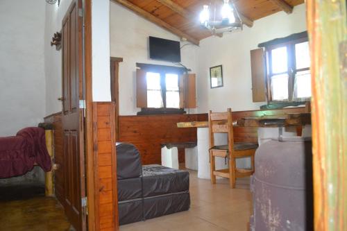salon z kanapą, stołem i oknami w obiekcie Cabañas Los Relinchos w mieście Capilla del Monte