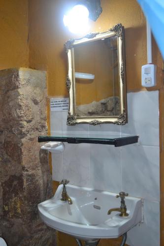 een badkamer met een wastafel en een spiegel aan de muur bij Cabañas Los Relinchos in Capilla del Monte