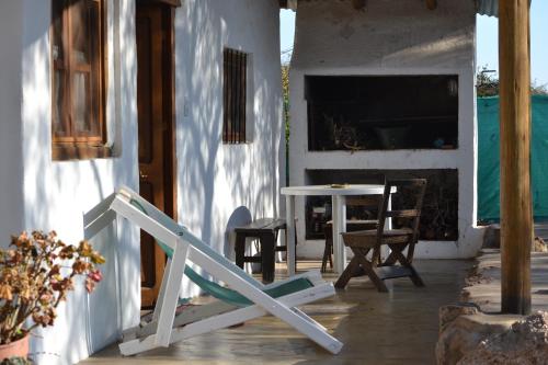 une véranda avec une table et des chaises et une maison blanche dans l'établissement Cabañas Los Relinchos, à Capilla del Monte