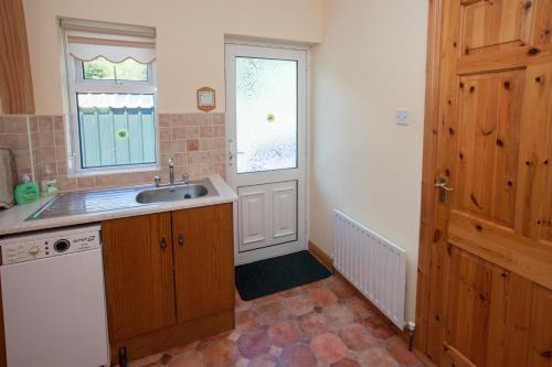 cocina con fregadero, ventana y puerta en Cottage 390 - Maam, en Claggan