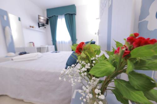a bedroom with a bed and a vase with flowers at Hotel Magna Grecia in Leuca