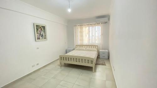 Habitación blanca con cama y ventana en Adriatik Apartment, en Durrës